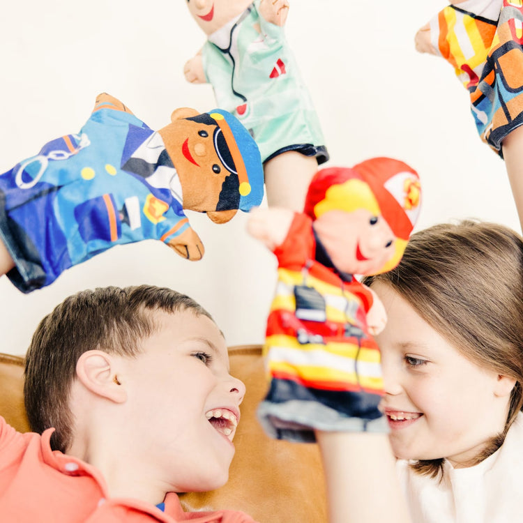 A kid playing with the Melissa & Doug Jolly Helpers Hand Puppets (Set of 4) - Construction Worker, Doctor, Police Officer, and Firefighter