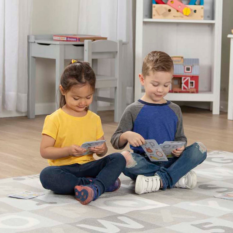 A kid playing with the Melissa & Doug Jumbo ABC-123 Rug Neutral (58 x 79 inches – 36 Game Cards)