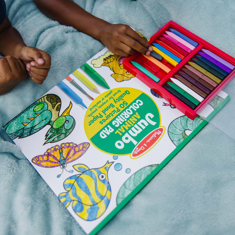 A kid playing with the Melissa & Doug Jumbo Coloring Pad (11 x 14 inches) - Animals, 50 Pictures