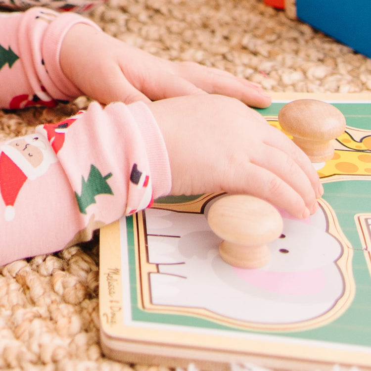 A kid playing with the Melissa & Doug Jungle Friends Safari Animals Jumbo Knob Wooden Puzzle