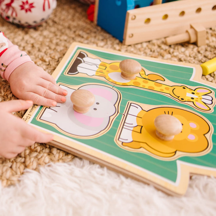 A kid playing with the Melissa & Doug Jungle Friends Safari Animals Jumbo Knob Wooden Puzzle