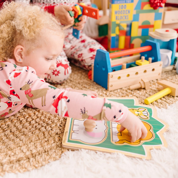 A kid playing with the Melissa & Doug Jungle Friends Safari Animals Jumbo Knob Wooden Puzzle