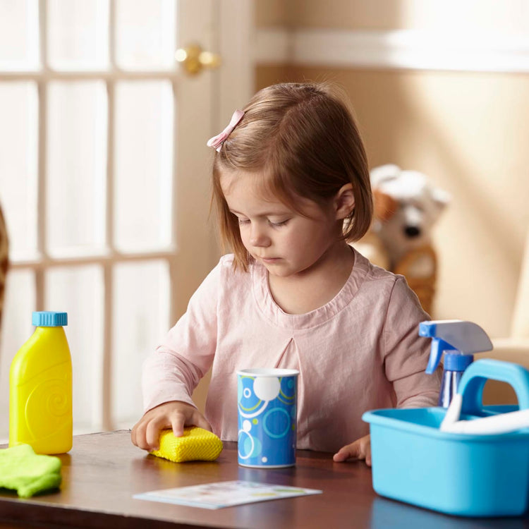 A kid playing with the Melissa & Doug Spray, Squirt & Squeegee Play Set - Pretend Play Cleaning Set