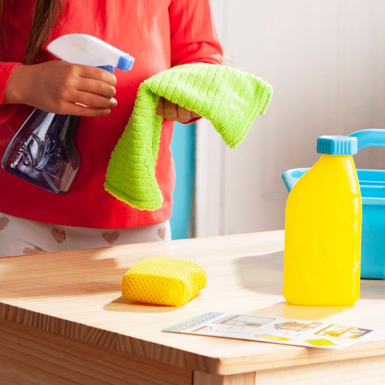 A kid playing with the Melissa & Doug Spray, Squirt & Squeegee Play Set - Pretend Play Cleaning Set