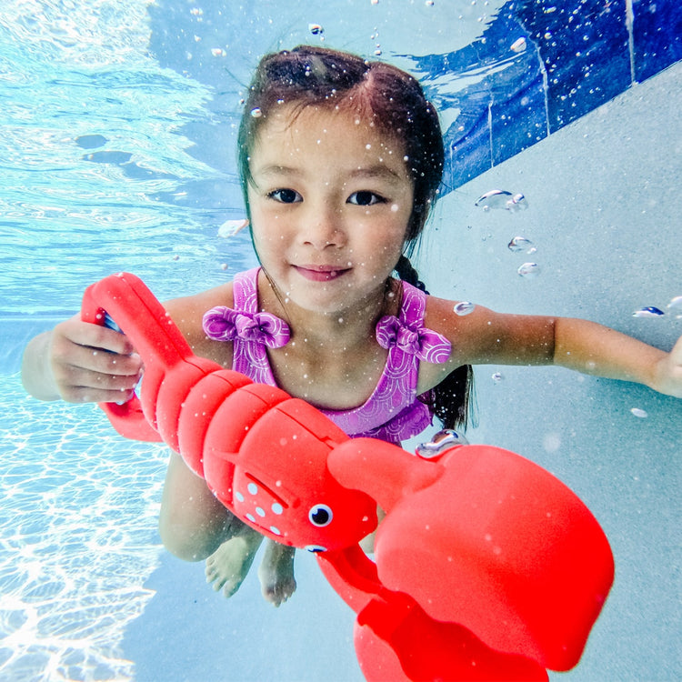 A kid playing with the Melissa & Doug Sunny Patch Louie Lobster Claw Catcher - Grab-and-Squeeze Pool Toy