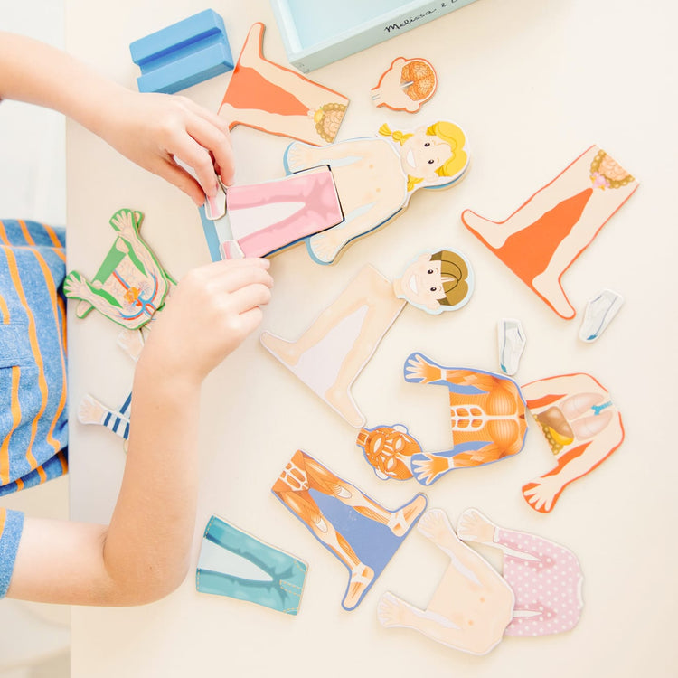 A kid playing with the Melissa & Doug Magnetic Human Body Anatomy Play Set With 24 Magnetic Pieces and Storage Tray