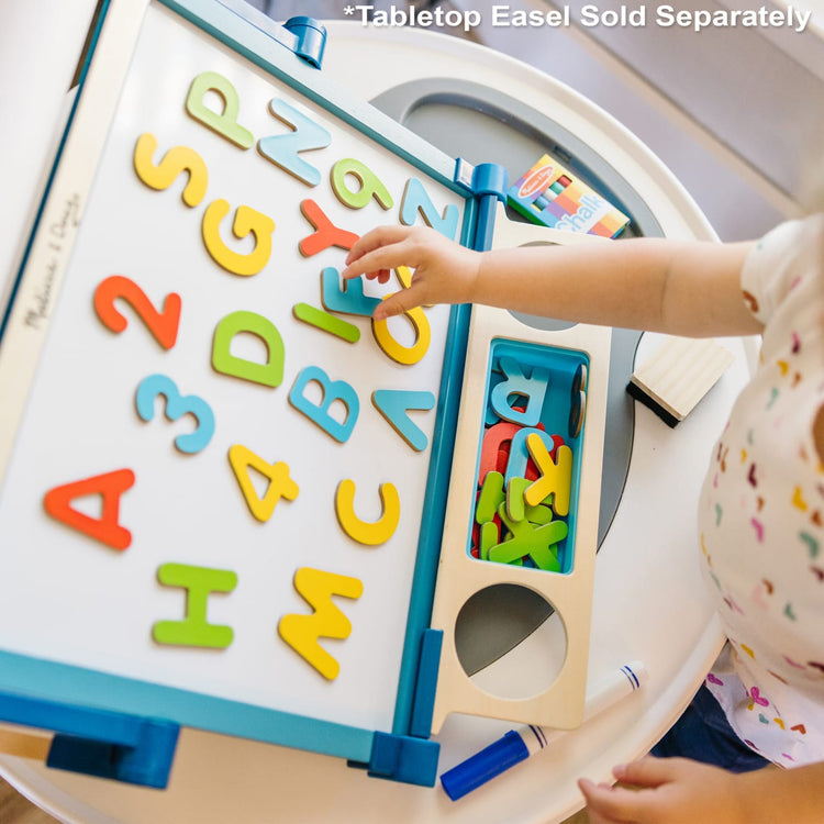 A kid playing with the Melissa & Doug Wooden Magnetic Letters and Numbers 2-Pack (89 Magnets)