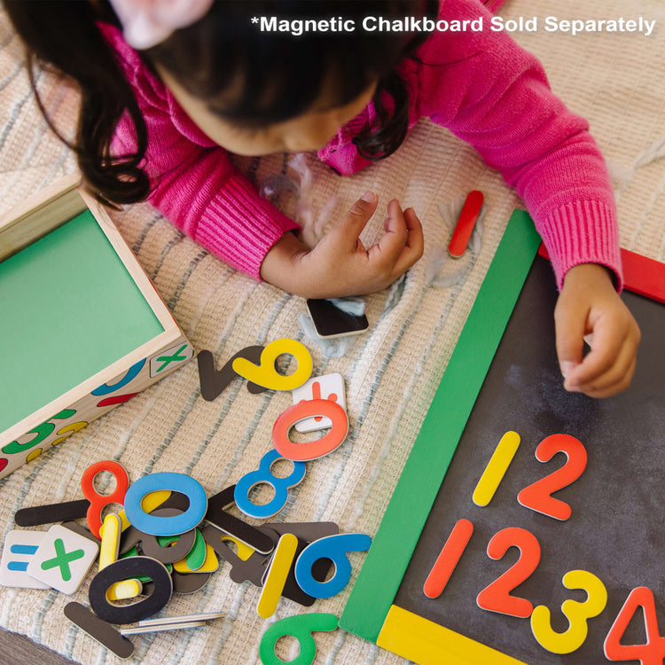 A kid playing with the Melissa & Doug Wooden Magnetic Letters and Numbers 2-Pack (89 Magnets)