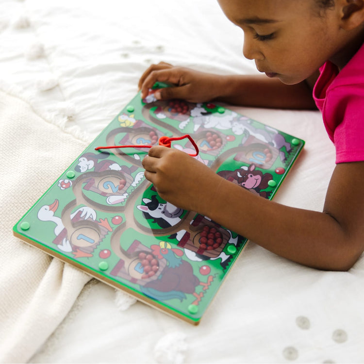 A kid playing with the Melissa & Doug Magnetic Wand Number Maze - Wooden Puzzle Activity