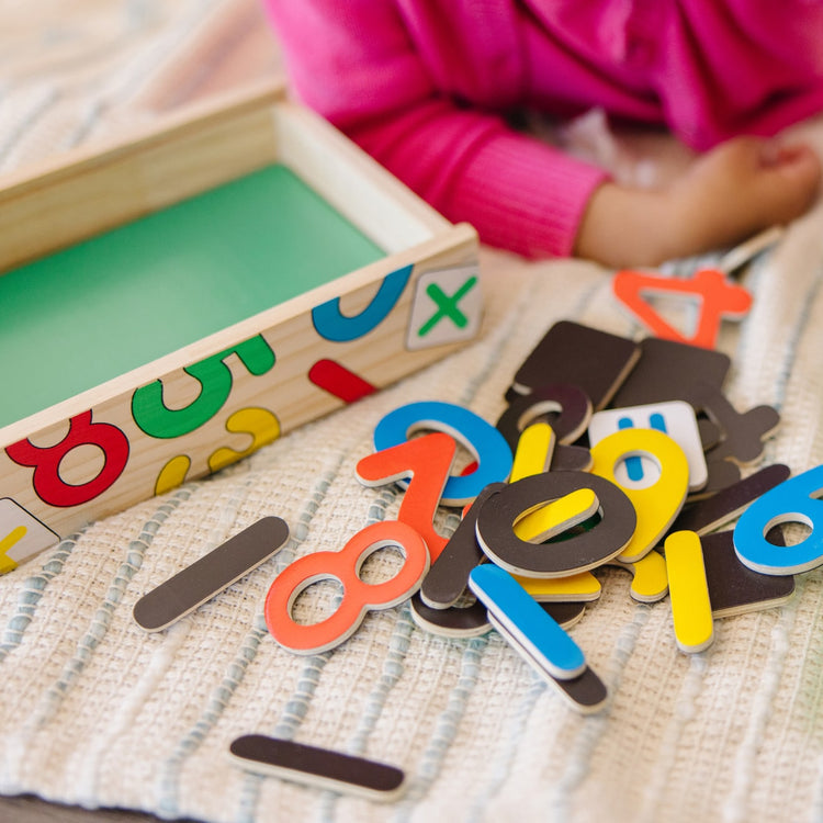 A kid playing with the Melissa & Doug 37 Wooden Number Magnets in a Box