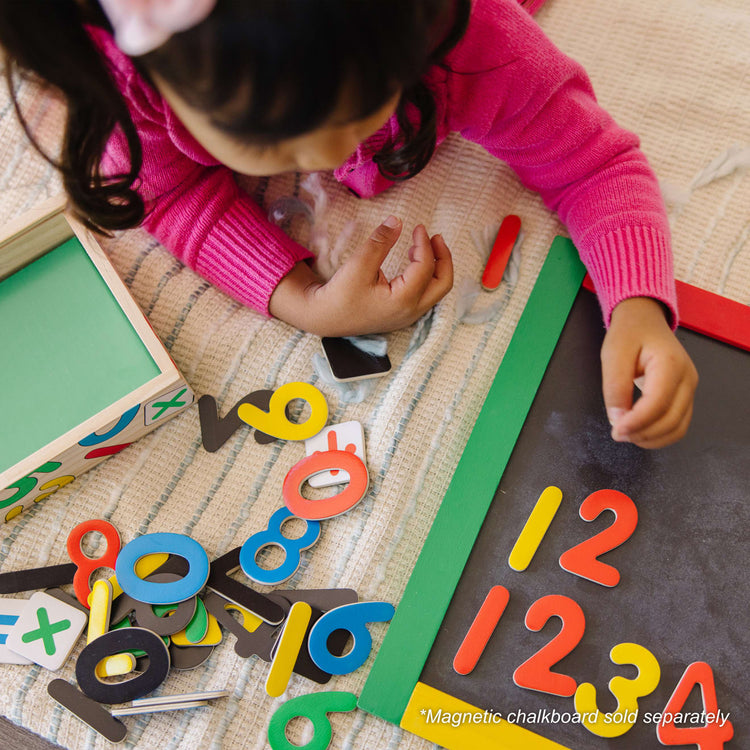 A kid playing with the Melissa & Doug 37 Wooden Number Magnets in a Box