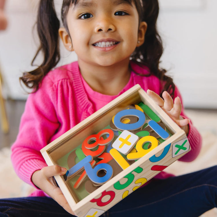 A kid playing with the Melissa & Doug 37 Wooden Number Magnets in a Box