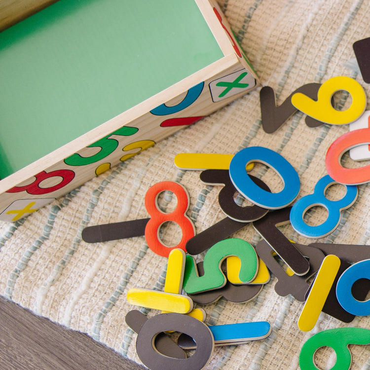 A kid playing with the Melissa & Doug 37 Wooden Number Magnets in a Box