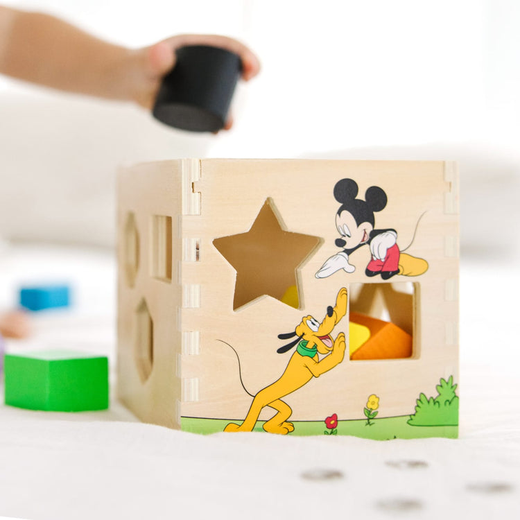 A kid playing with the Mickey Mouse & Friends Wooden Shape Sorting Cube