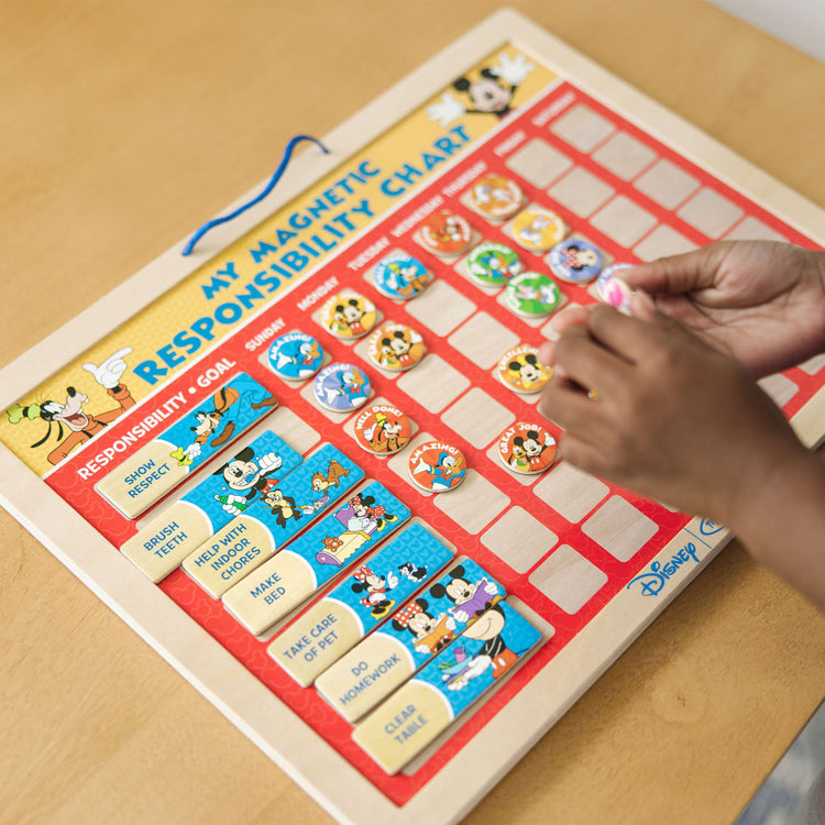 A kid playing with the Melissa & Doug Disney Mickey Mouse Clubhouse My Magnetic Responsibility Chart