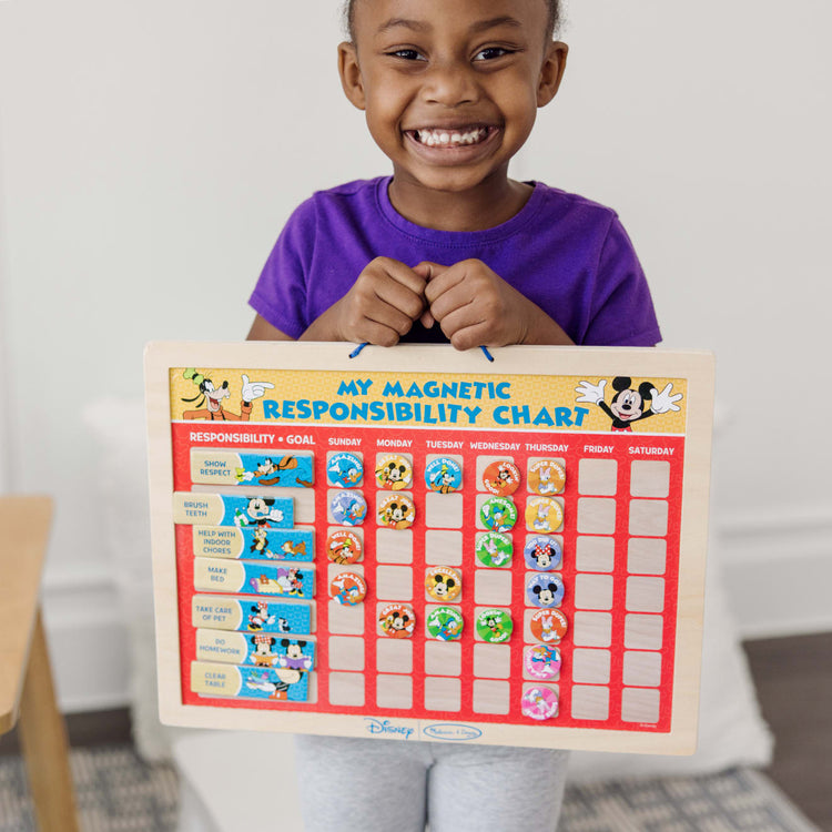 A kid playing with the Melissa & Doug Disney Mickey Mouse Clubhouse My Magnetic Responsibility Chart