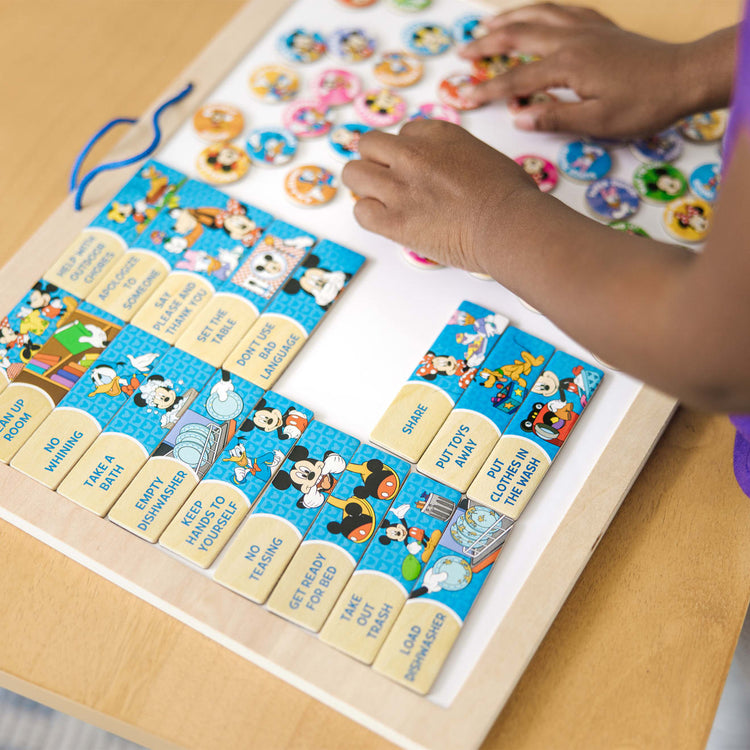 A kid playing with the Melissa & Doug Disney Mickey Mouse Clubhouse My Magnetic Responsibility Chart