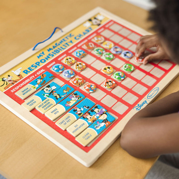 A kid playing with the Melissa & Doug Disney Mickey Mouse Clubhouse My Magnetic Responsibility Chart