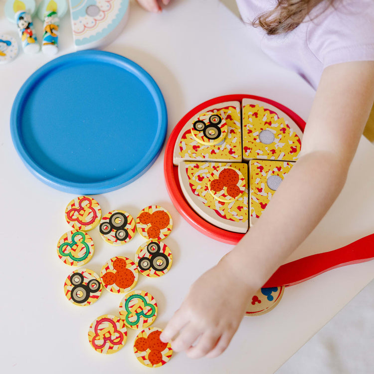 A kid playing with the Melissa & Doug Mickey Mouse Wooden Pizza and Birthday Cake Set (32 pcs) - Play Food