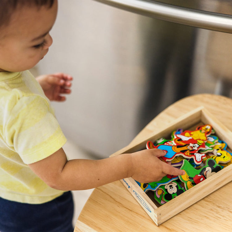 A kid playing with the Melissa & Doug Disney Mickey Mouse Clubhouse Wooden Character Magnets (20 pcs)