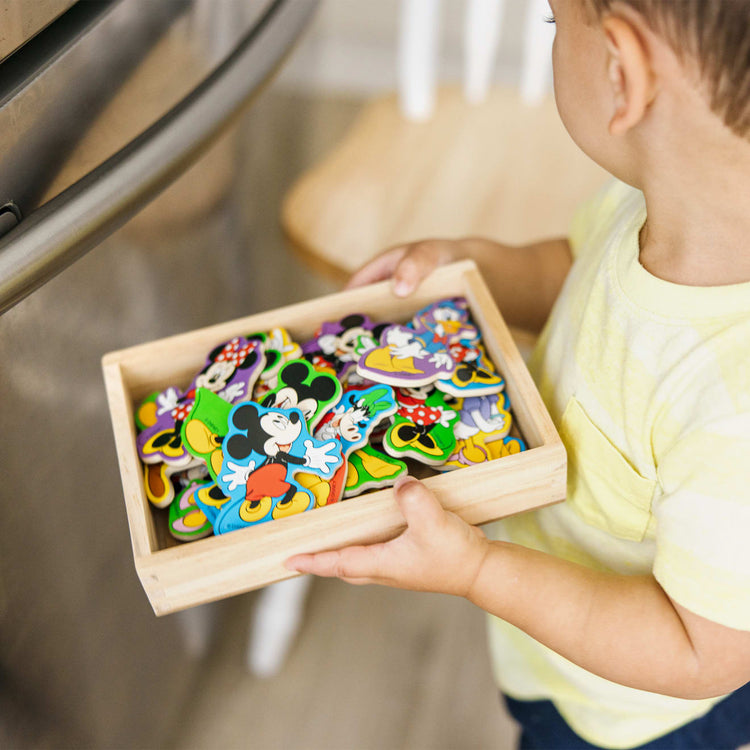 A kid playing with the Melissa & Doug Disney Mickey Mouse Clubhouse Wooden Character Magnets (20 pcs)