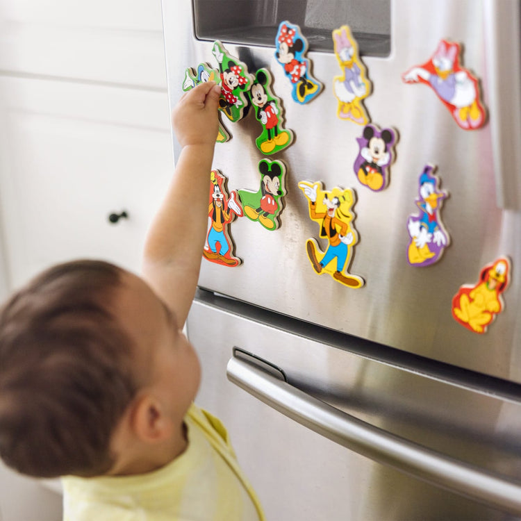 A kid playing with the Melissa & Doug Disney Mickey Mouse Clubhouse Wooden Character Magnets (20 pcs)