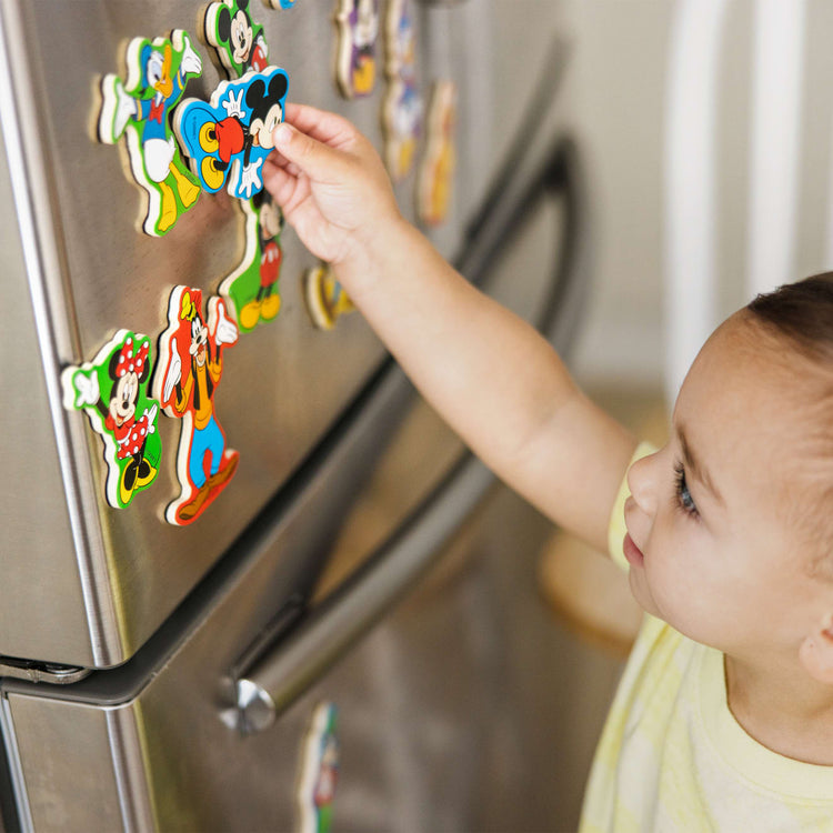 A kid playing with the Melissa & Doug Disney Mickey Mouse Clubhouse Wooden Character Magnets (20 pcs)