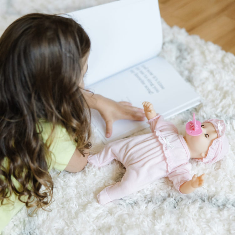 A kid playing with the Melissa & Doug Mine to Love Jenna 12" Soft Body Baby Doll With Romper, Hat