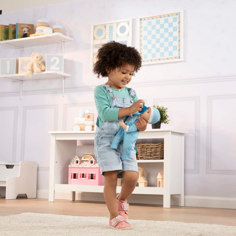 A kid playing with the Melissa & Doug Mine to Love Jordan 12” Light Skin-Tone Boy Baby Doll with Romper, Cap, Pacifier