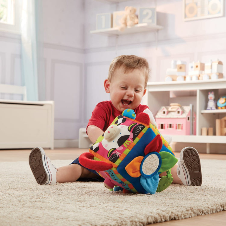 A kid playing with the Melissa & Doug K's Kids Musical Farmyard Cube Educational Baby Toy