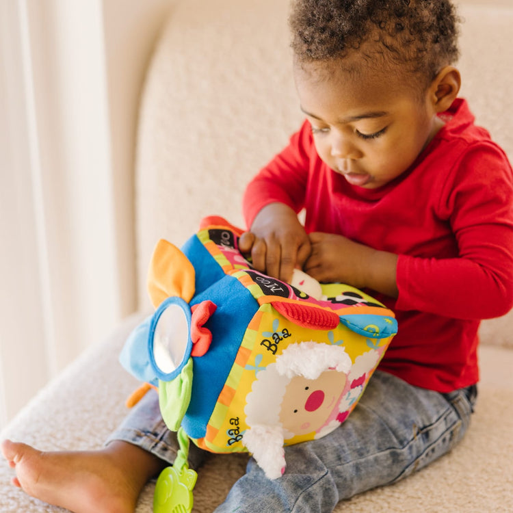 A kid playing with the Melissa & Doug K's Kids Musical Farmyard Cube Educational Baby Toy