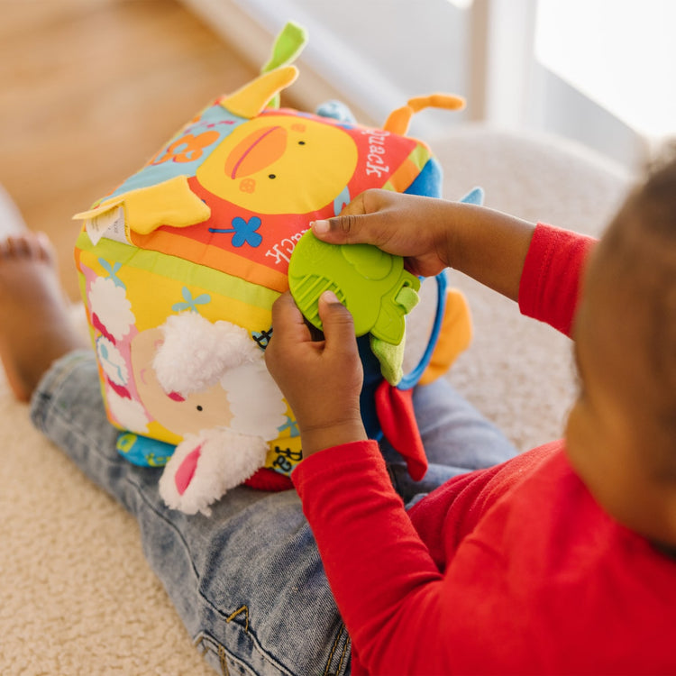 A kid playing with the Melissa & Doug K's Kids Musical Farmyard Cube Educational Baby Toy