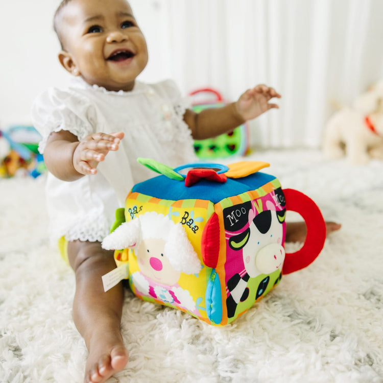 A kid playing with the Melissa & Doug K's Kids Musical Farmyard Cube Educational Baby Toy