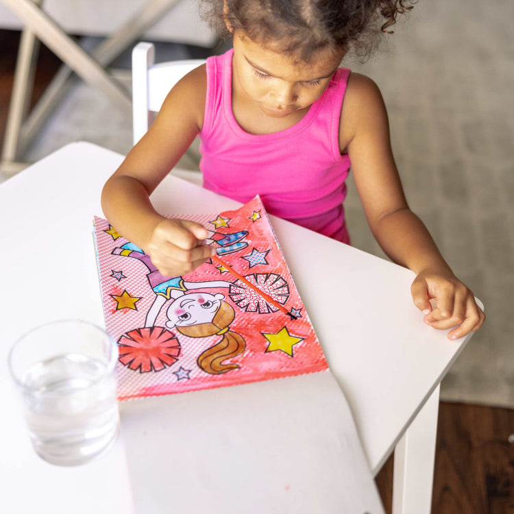 A kid playing with the Melissa & Doug My First Paint With Water Art Pad - Cheerleaders, Flowers, Fairies, and More (24 Pages)