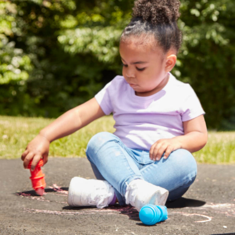 A kid playing with the Melissa & Doug My First Sidewalk Chalk Set With Holders - 4 Chalk Sticks and 4 Holders