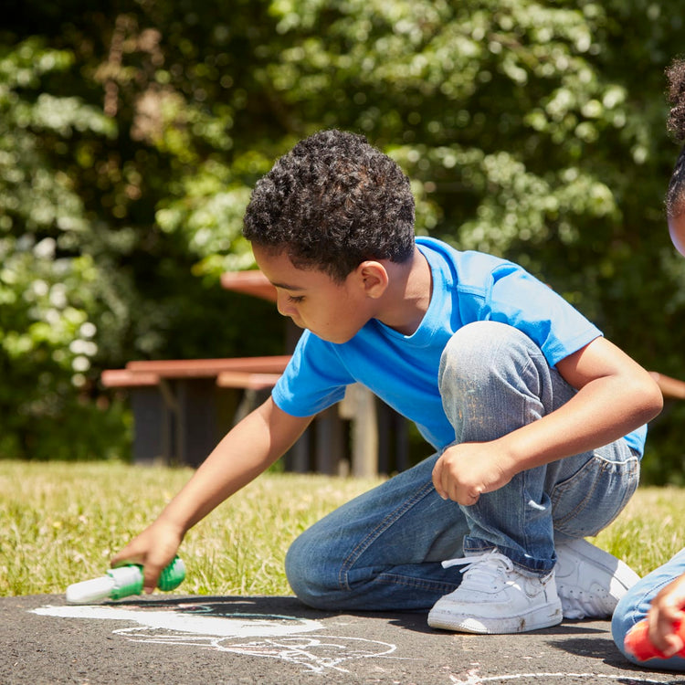 A kid playing with the Melissa & Doug My First Sidewalk Chalk Set With Holders - 4 Chalk Sticks and 4 Holders