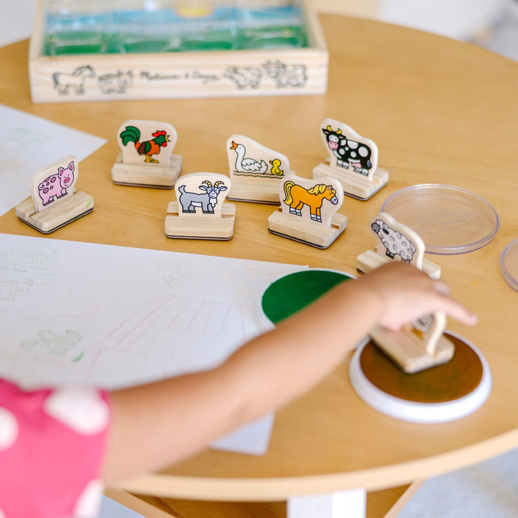 A kid playing with the Melissa & Doug My First Wooden Stamp Set - Farm Animals