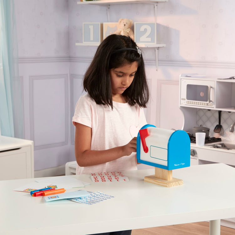 A kid playing with the Melissa & Doug My Own Wooden Mailbox Activity Set and Educational Toy