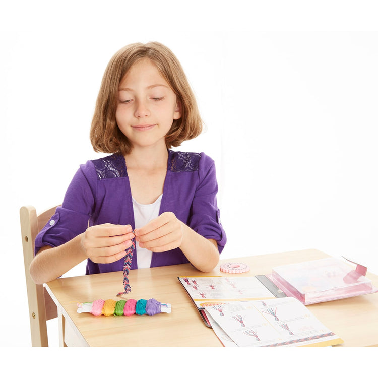 A child on white background with the Melissa & Doug On the Go Friendship Bracelet Craft Set (Makes 10+ Bracelets)