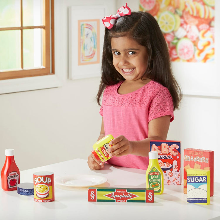 A kid playing with the Melissa & Doug Wooden Pantry Products Play Food Set (9 pcs)