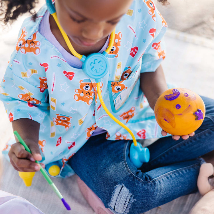 A kid playing with the Melissa & Doug Pediatric Nurse Costume Role Play Set (8 pcs) - Includes Baby Doll, Stethoscope