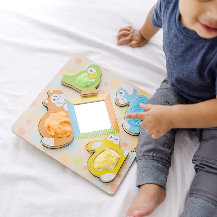 A kid playing with the Melissa & Doug First Play Wooden Touch and Feel Puzzle Peek-a-Boo Pets With Mirror