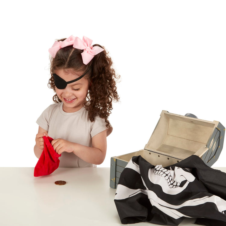 A child on white background with the Melissa & Doug Wooden Pirate Chest Pretend Play Set