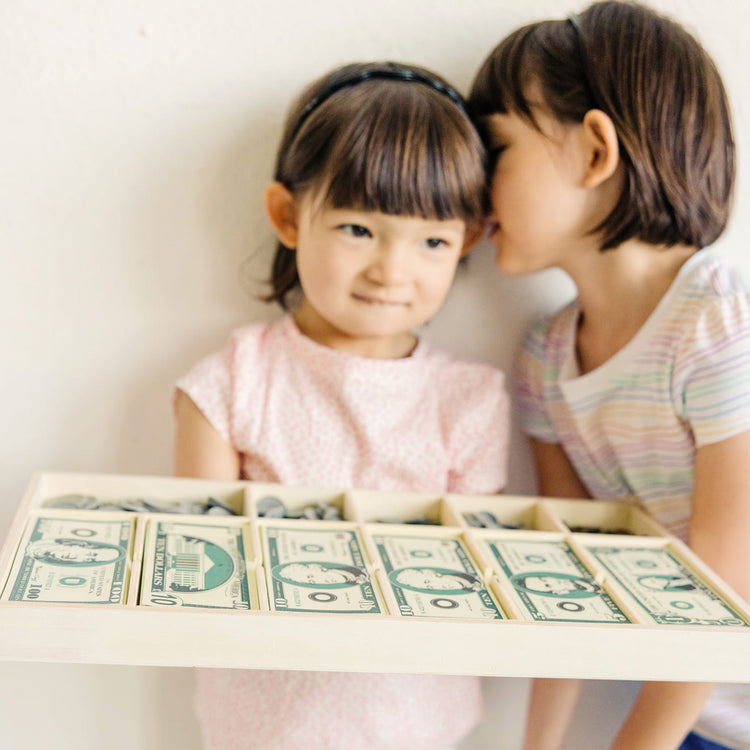 A kid playing with the Melissa & Doug Play Money Set - Educational Toy With Paper Bills and Plastic Coins (50 of Each Denomination) and Wooden Cash Drawer for Storage