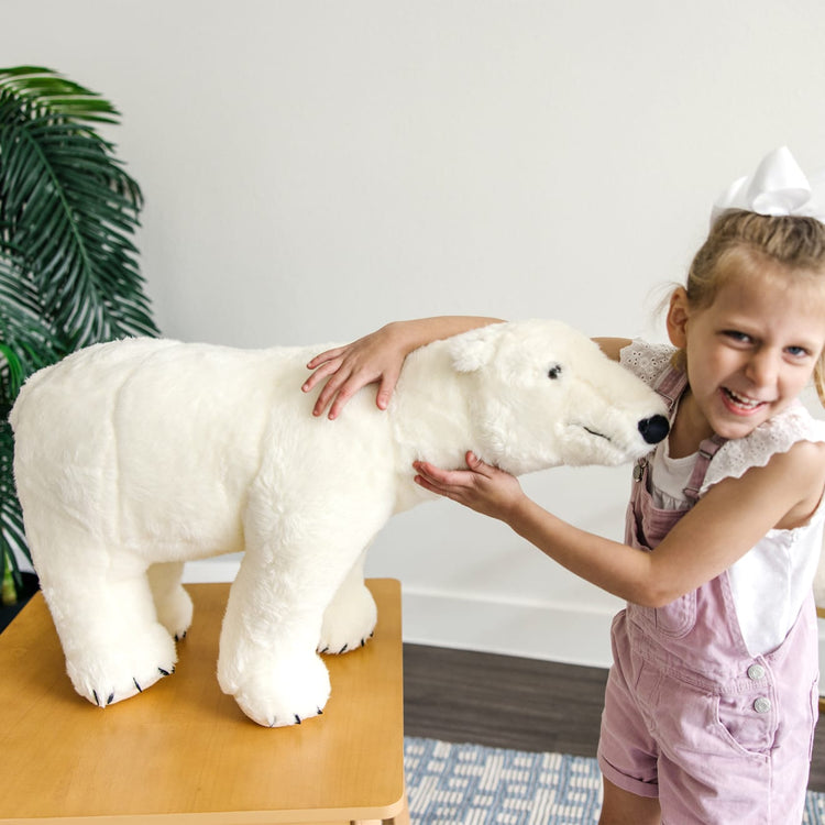 A kid playing with the Melissa & Doug Giant Polar Bear - Lifelike Stuffed Animal (nearly 3 feet long)