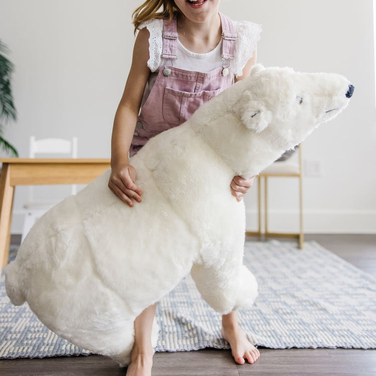 A kid playing with the Melissa & Doug Giant Polar Bear - Lifelike Stuffed Animal (nearly 3 feet long)