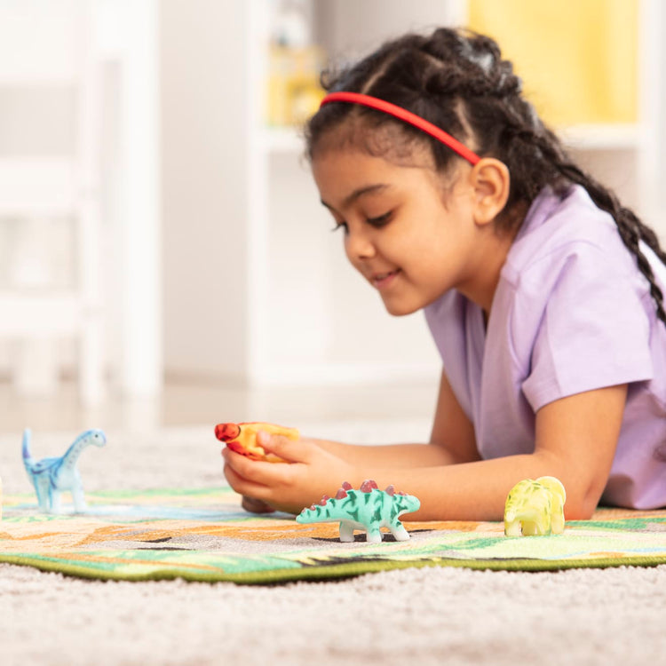 A kid playing with the Melissa & Doug Prehistoric Playground Dinosaur Activity Rug (39 x 36 inches) - 4 Toy Animals