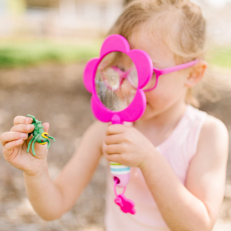 A kid playing with the Melissa & Doug Sunny Patch Pretty Petals Flower Magnifying Glass With Shatterproof Lens