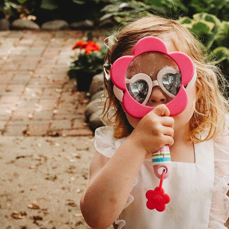 A kid playing with the Melissa & Doug Sunny Patch Pretty Petals Flower Magnifying Glass With Shatterproof Lens