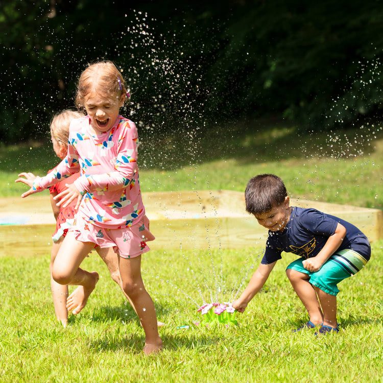 A kid playing with the Melissa & Doug Sunny Patch Pretty Petals Flower Sprinkler Toy With Hose Attachment